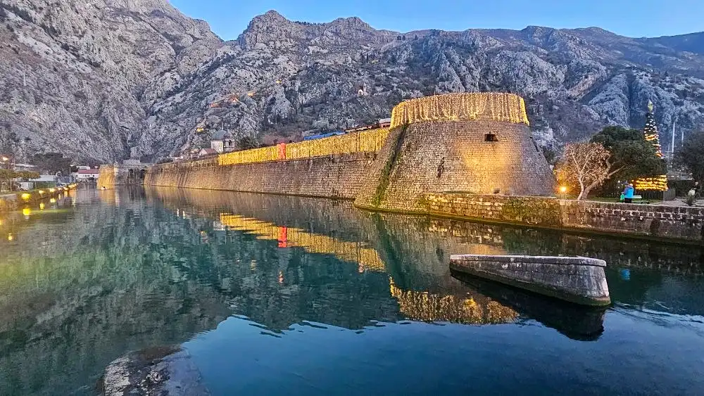 Kotor city walls lit at dusk and reflected in the Bay of Kotor