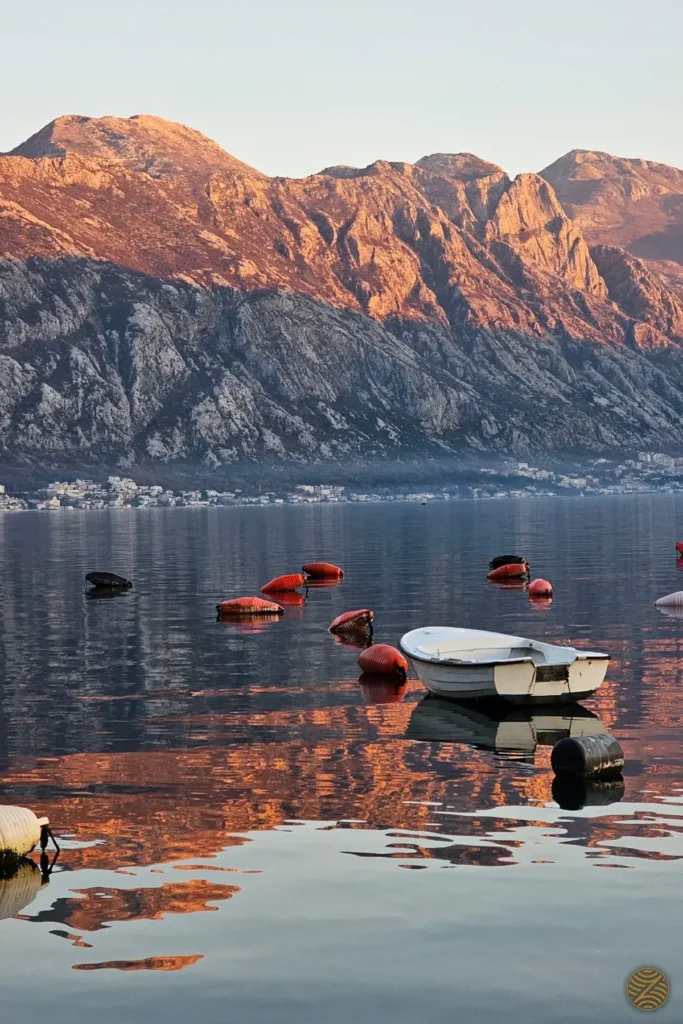 Evening light on the mountains above the Bay of Kotor, with a small boat among shellfish-farm buoys