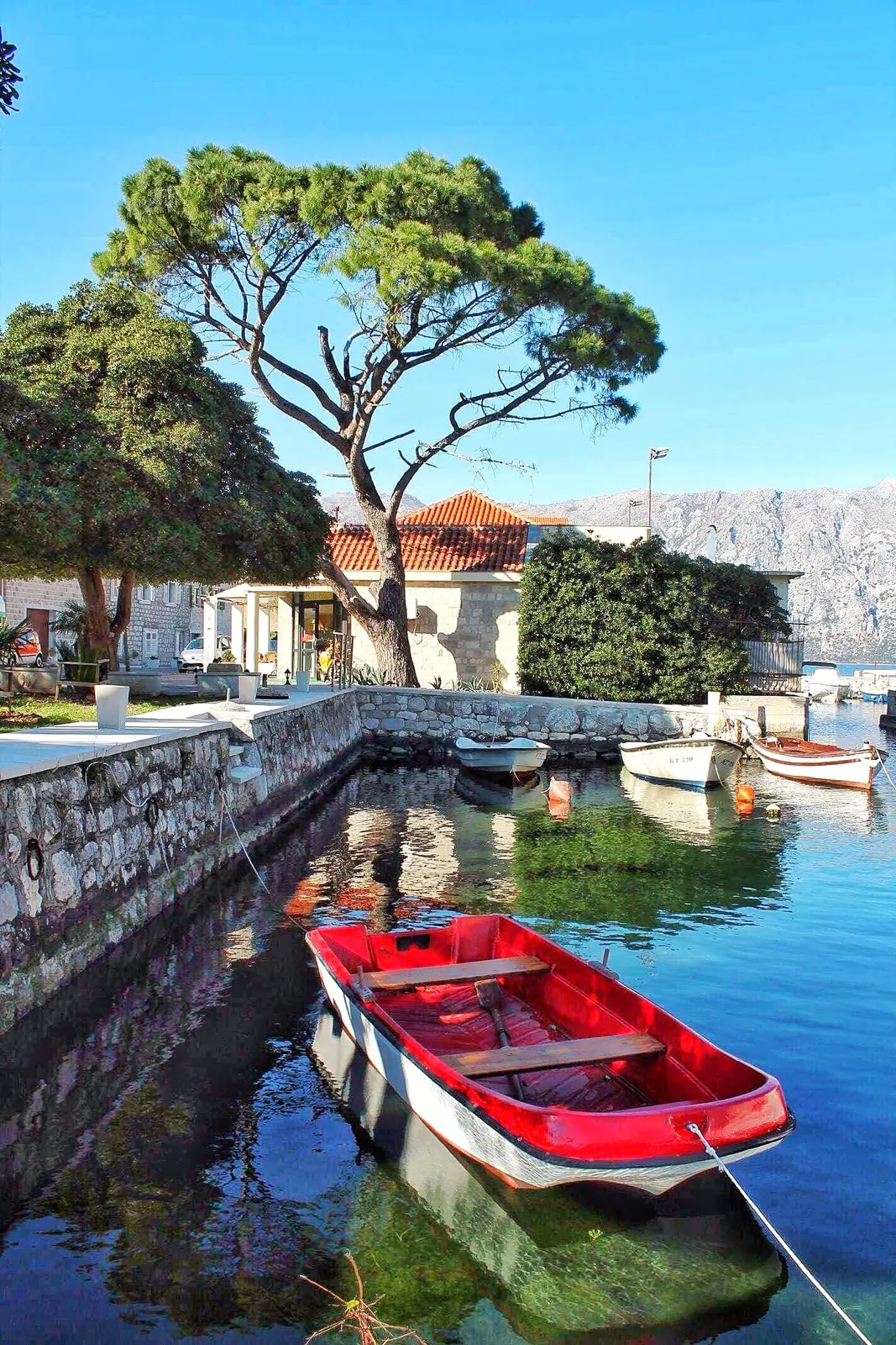 Red rowing boat moored by a stone quay in the Bay of Kotor, Montenegro