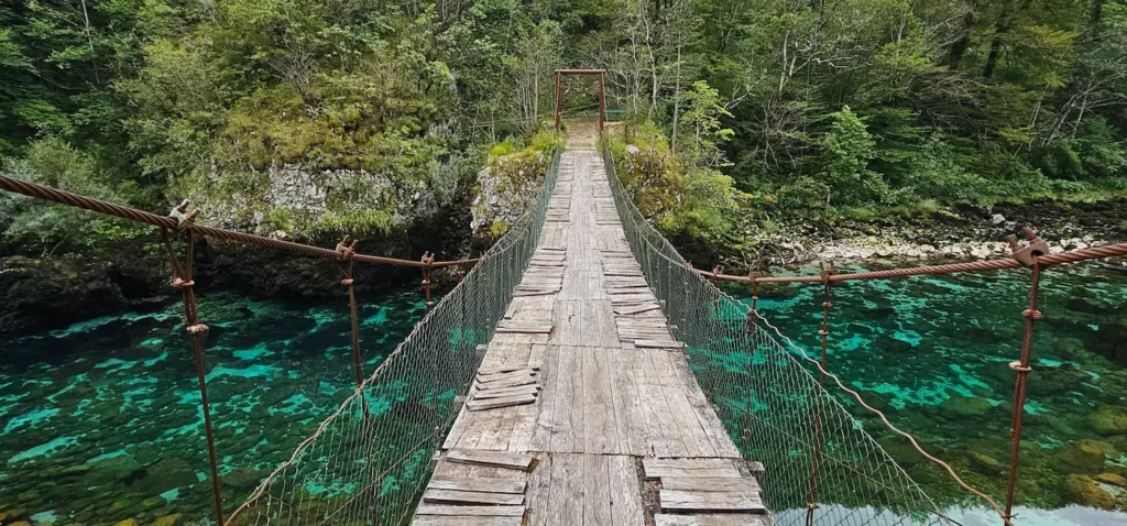 Wooden suspension bridge over a turquoise mountain river in Montenegro