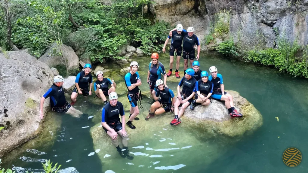 Canyoning group in wetsuits and helmets standing in a forest river in Montenegro