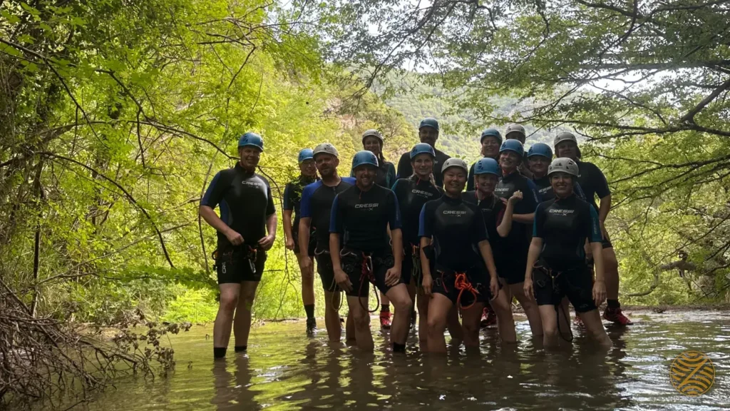 Canyoning group resting on rocks in a green river pool in Montenegro