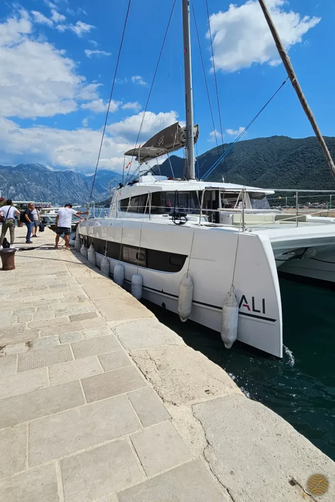 Sailing catamaran moored at a stone quay in the Bay of Kotor, ready for a private charter