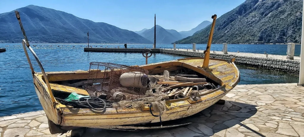 Old wooden fishing boat with nets on a stone quay in the Bay of Kotor