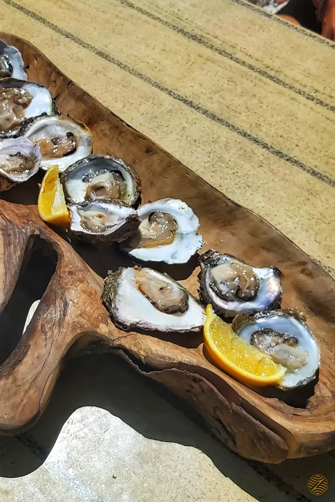 Fresh Boka oysters with lemon on a rustic wooden board, Montenegro