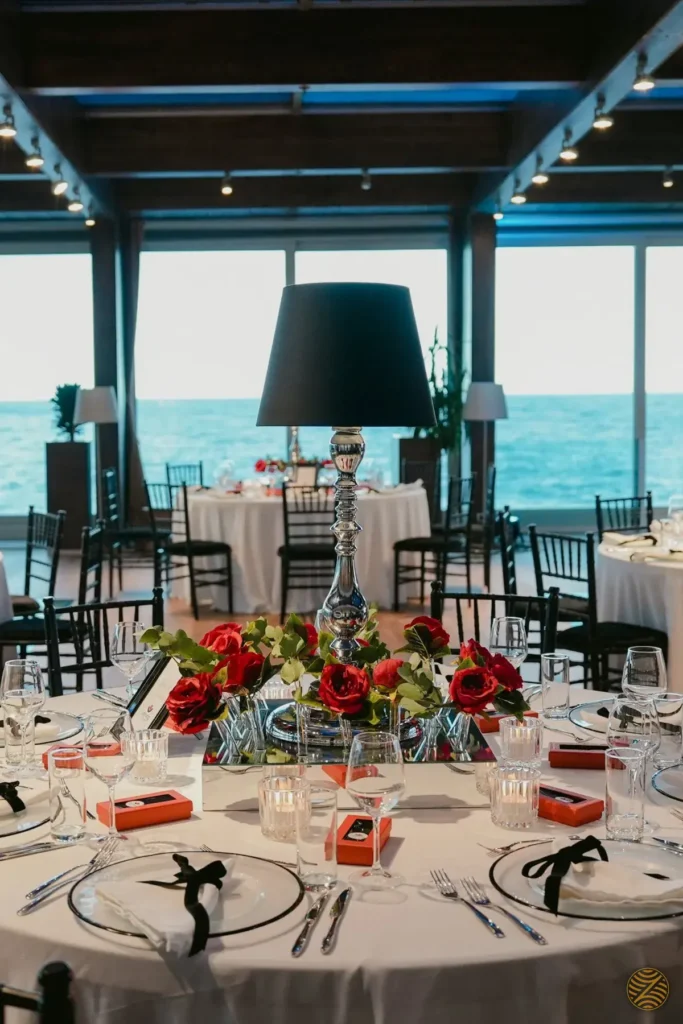 Gala dinner tables with red roses in a glass-walled venue overlooking the Adriatic Sea, Montenegro