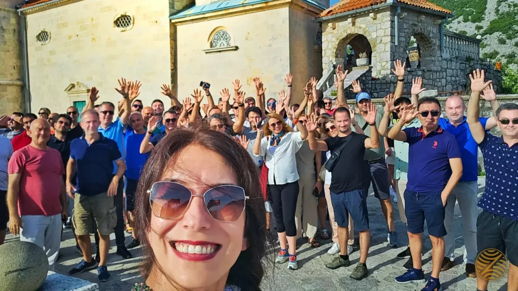 Our founder Deniz Gönenç with a waving tour group on the island of Our Lady of the Rocks, Perast