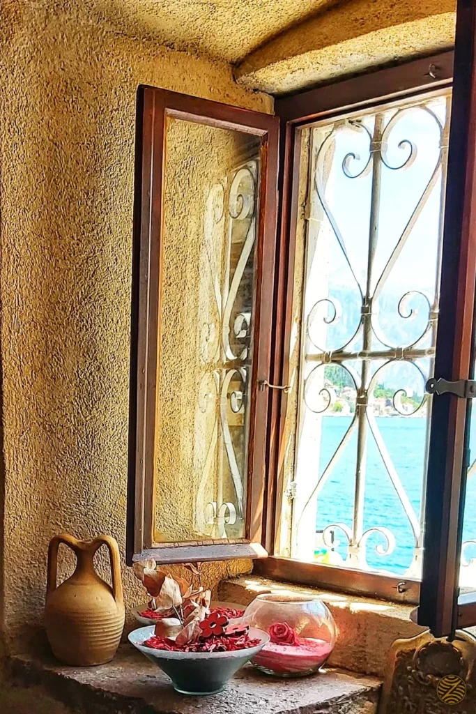Old stone window with a wrought-iron grille looking out over the Bay of Kotor in Perast