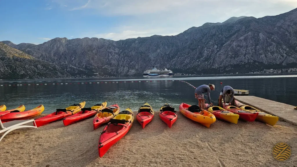Sea kayaks lined up on a beach in the Bay of Kotor, ready for a morning paddle