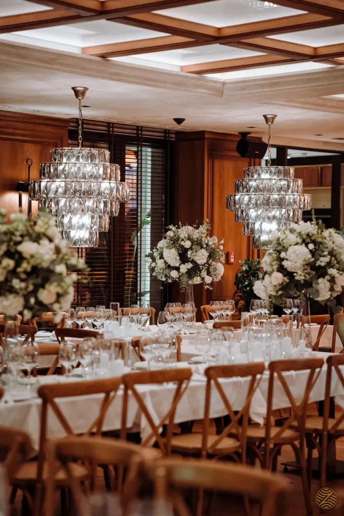 Reception hall with crystal chandeliers, white flower arrangements and long dinner tables in Montenegro